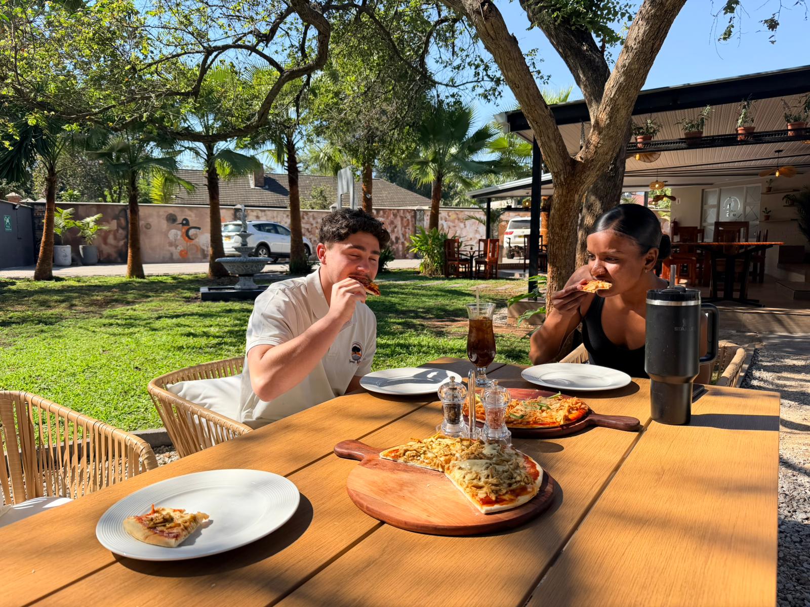 Guests enjoying pizza at Kori Studio's sunlit garden dining area